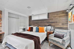 Bedroom featuring carpet, a closet, and wood walls