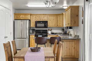 Kitchen featuring light brown cabinetry, sink, a notable chandelier, and black appliances