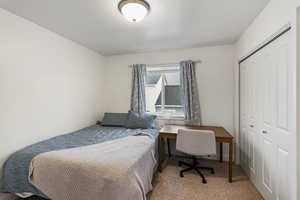 Bedroom with light colored carpet, a textured ceiling, and a closet