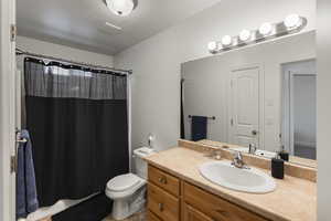 Bathroom with vanity, curtained shower, toilet, and a textured ceiling