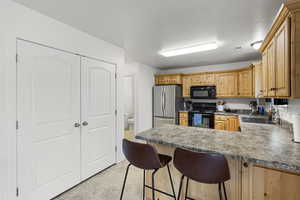 Kitchen with a kitchen bar, sink, black appliances, and a textured ceiling