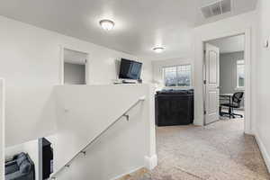 Hallway with a textured ceiling and carpet floors