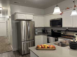 Kitchen featuring white cabinetry, pendant lighting, dark hardwood / wood-style floors, and appliances with stainless steel finishes