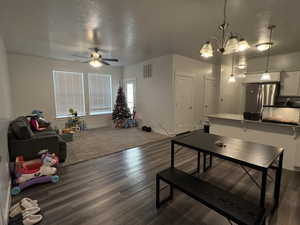 Interior space with ceiling fan with notable chandelier, a textured ceiling, and dark hardwood / wood-style flooring