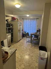 Kitchen featuring a textured ceiling and white refrigerator with ice dispenser