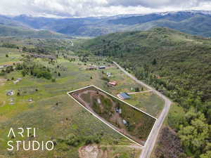 View of rural area with property parcel outlined, a mountain backdrop, and a forest