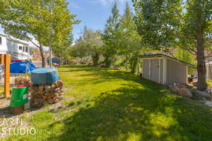 View of green lawn with a storage shed and an outdoor pump house
