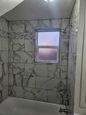 Bathroom featuring tiled shower / bath combo and a textured ceiling