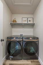 Clothes washing area with washing machine and dryer and hardwood / wood-style flooring