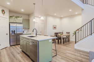 Kitchen with pendant lighting, a kitchen island with sink, appliances with stainless steel finishes, and a breakfast bar area