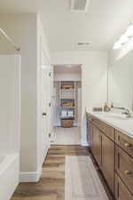 Bathroom with vanity, wood-type flooring, a textured ceiling, and shower / tub combination, a walk in closet, enclosed toilet room