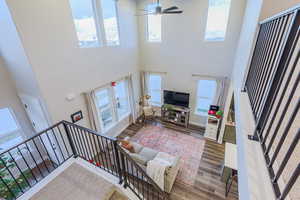 Living room with a high ceiling, hardwood / wood-style flooring, and ceiling fan