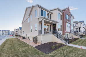 View of front of house featuring central air condition unit, covered porch, and a front yard