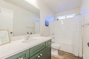 Full bathroom with shower / tub combo, vanity, hardwood / wood-style flooring, and toilet