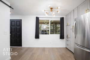 Interior space featuring a barn door, light hardwood / wood-style flooring, a textured ceiling, and a notable chandelier