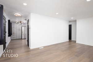 Empty room featuring a textured ceiling, light wood-type flooring, and crown molding