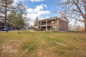 Back of house featuring a balcony and a lawn