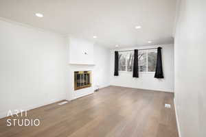 Unfurnished living room featuring hardwood / wood-style flooring and crown molding