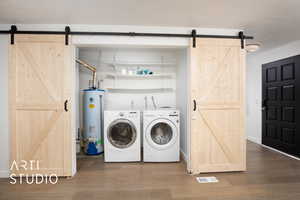 Laundry room with a barn door, water heater, and wood-type flooring