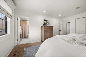 Bedroom featuring carpet flooring, ensuite bathroom, a closet, and ornamental molding