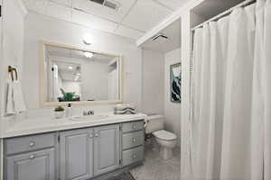 Bathroom featuring tile patterned floors, vanity, a paneled ceiling, and toilet