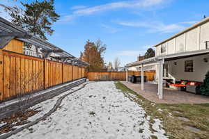 Yard covered in snow with a jacuzzi, a patio, and an outdoor hangout area