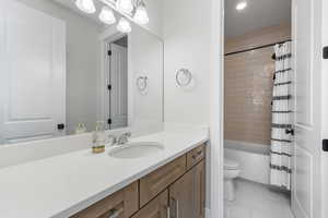 Full bathroom featuring vanity, toilet, and shower / bathtub combination with curtain