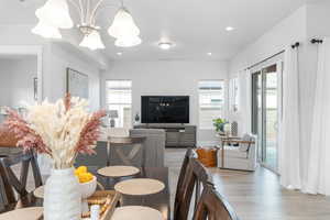 Dining area with light hardwood / wood-style floors, plenty of natural light, and a notable chandelier