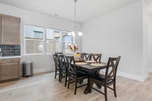 Dining room featuring light wood-type flooring and a notable chandelier