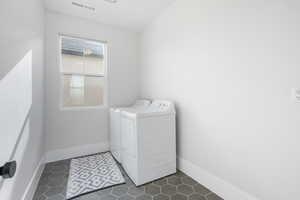 Laundry area with washer and clothes dryer and dark tile patterned flooring