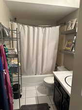 Full bathroom featuring vanity, tile patterned floors, shower / bath combination with curtain, toilet, and a textured ceiling