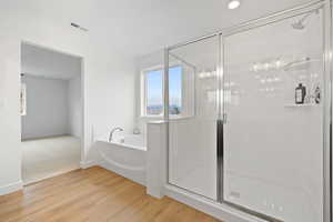 Bathroom with hardwood / wood-style floors and independent shower and bath