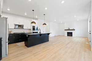 Kitchen with a kitchen island with sink, a breakfast bar area, decorative backsplash, light hardwood / wood-style floors, and stainless steel appliances