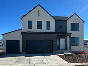 Modern farmhouse with metal roof, driveway, a standing seam roof, and an attached garage