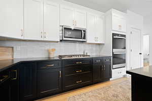 Kitchen with white cabinets, backsplash, light wood-type flooring, and stainless steel appliances