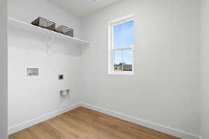 Laundry room with hookup for an electric dryer, light wood-type flooring, and hookup for a washing machine