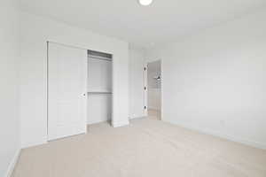 Unfurnished bedroom with light carpet and a closet