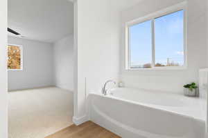 Bathroom featuring wood-type flooring and a tub to relax in