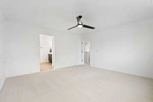 Unfurnished bedroom with ceiling fan, ensuite bathroom, and light carpet