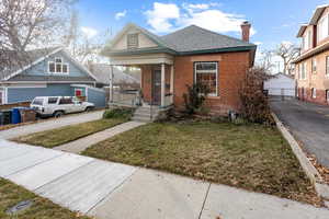 Bungalow-style house with a porch, a garage, a front lawn, and an outdoor structure