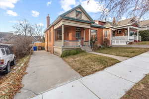 View of front of property with a porch and a front lawn