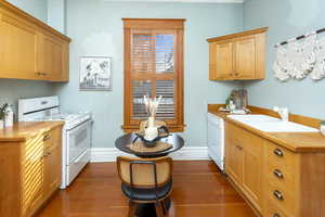 Kitchen with sink, white appliances, and dark wood-type flooring