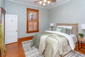 Bedroom featuring light hardwood / wood-style floors, ceiling fan, and crown molding