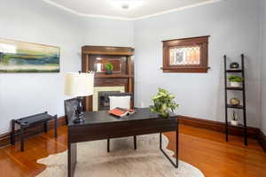 Office with wood-type flooring and crown molding