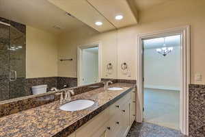 Bathroom featuring vanity, a chandelier, a shower with shower door, and toilet