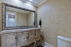 Bathroom with tile patterned floors, vanity, toilet, and crown molding