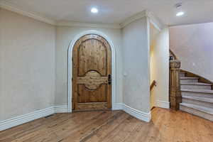 Foyer with crown molding and light hardwood / wood-style floors