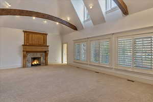 Unfurnished living room with plenty of natural light, a fireplace, and light carpet