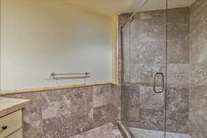 Bathroom featuring vanity, tile walls, and a shower with shower door