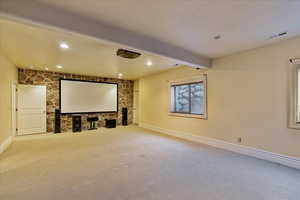 Carpeted home theater room with beam ceiling